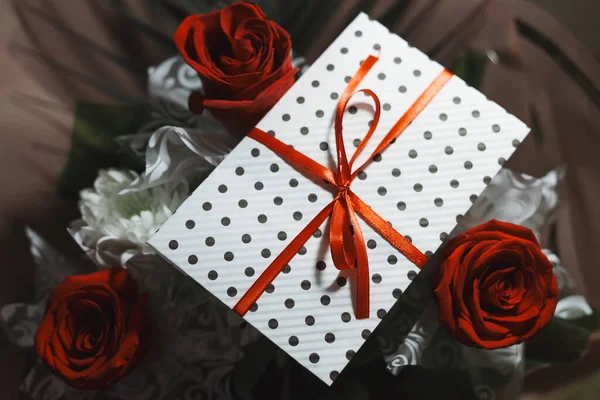 ギフト封筒 赤いリボン 証明書のための白い紙 中への招待カードを持つ3赤いバラの花束 工芸の概念 赤の背景に赤 ウェディグ式のコンセプト休日の驚き — ストック写真