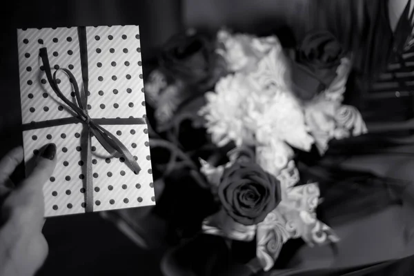 ホワイト ギフト 封筒に証明書の白い紙のリボン女性の手の中への招待状 工芸の概念 ウェディグ式のコンセプト休日の驚き 白黒写真 — ストック写真