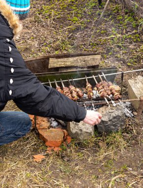 Doğada bahçede dinlenirken, şiş kebap yerken, av kupası pişirirken, ateşte kebap pişirirken, adam kebapları ateşe veriyor.