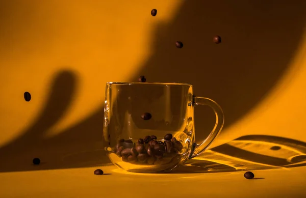 Lewitujące ziarna kawy w przezroczystej szklance — Zdjęcie stockowe