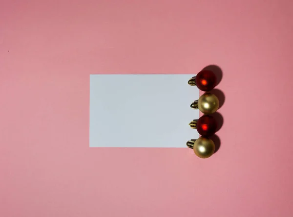 Świąteczna kartka na różowym tle z kulkami choinkowymi — Zdjęcie stockowe