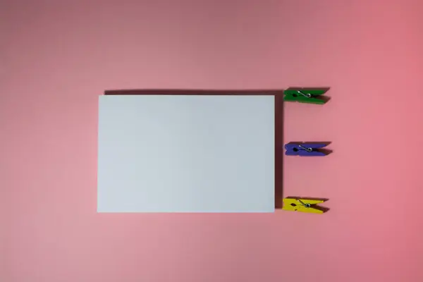 Plancha creativa con una postal y pinzas de ropa multicolores — Foto de Stock