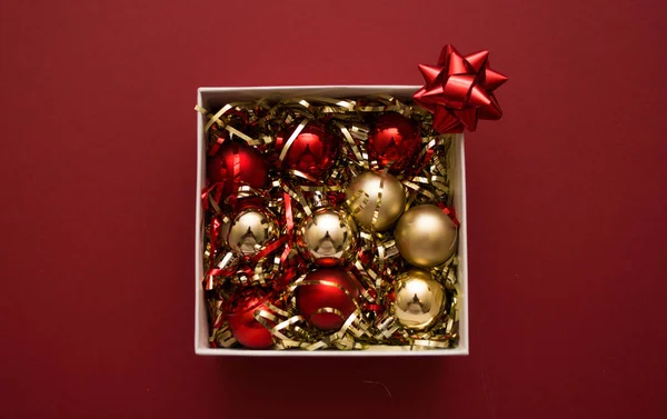 赤い背景にクリスマスのおもちゃとティンセル付きの白いギフトボックス — ストック写真