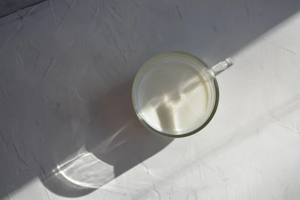 Молоко в склянці на сірому фоні з жорстким світлом. Вид зверху . — стокове фото