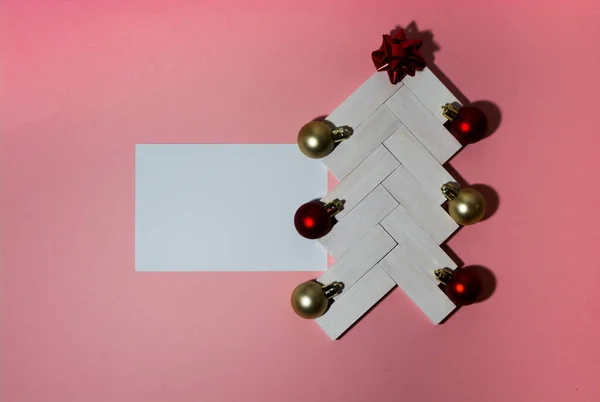 白いバーと黄色のボールとピンクの背景の上にテキストのための場所と弓で作られた即興のクリスマスツリーの創造的なイメージ。上からの眺め — ストック写真