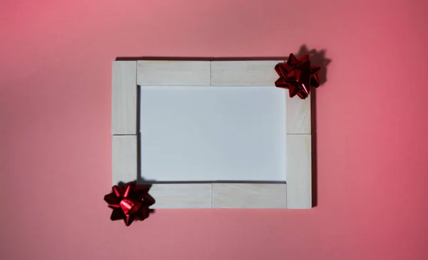 Біло-блокова листівка, прикрашена бантом на рожевому фоні — стокове фото