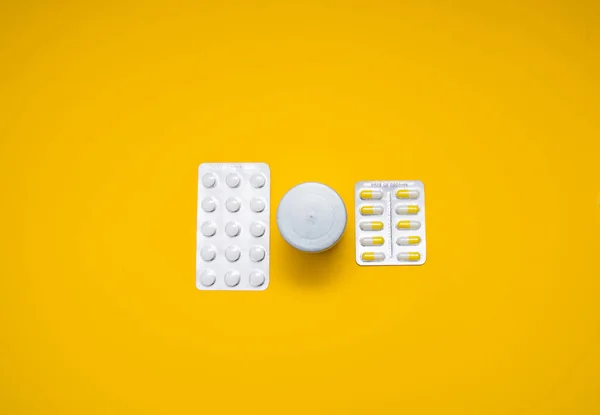 Cápsulas médicas, pastillas sobre fondo amarillo. — Foto de Stock