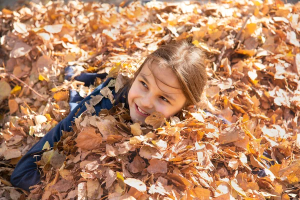 Улыбающаяся Девушка Лежит Куче Золотых Осенних Листьев — стоковое фото