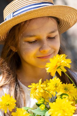 Hasır şapkalı, uzun saçlı ve sarı çiçekli gülümseyen bir kız. Yaz konsepti