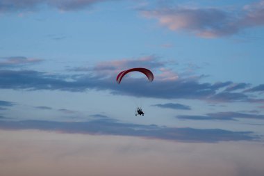Yamaç paraşütü gökyüzünde yükseklere uçuyor. Günbatımı gökyüzünün arka planında paraglider. Ekstrem spor kavramı.