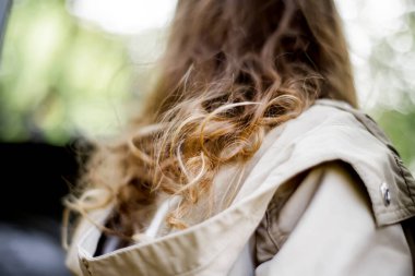 Açık kahverengi saçlı şirin bir kız askeri teçhizat deposunda sonbahar parkında yürüyor..