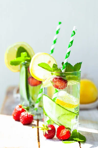 Refreshing cold summer drink: cucumber lemonade with strawberry, lemon, lime, mint in a glass. Detox, light beverage with natural organic ingredients for hot weather. Close up macro copy space