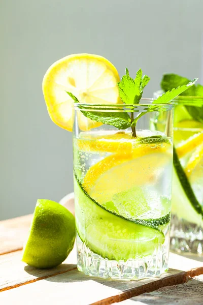 Refreshing cold summer drink: cucumber lemonade with lemon, lime and mint in a glass. Detox, light beverage with natural organic ingredients for hot weather. Close up macro copy space