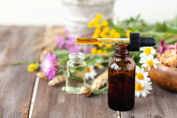 Concept of herbal, flower extracts in cosmetics. Natural organic ingredients, pure extract for beautiful healthy skin, essential oil, aromatherapy. Wooden background, close up