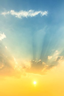 Parlak gün batımı turuncu güneş ışığı mavi gökyüzünde yumuşak bulutlar ve güneş ışınlarıyla