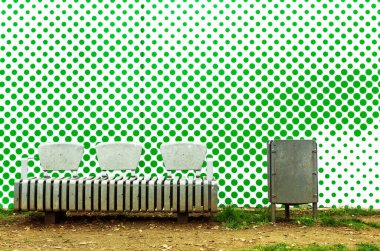 Arka plandaki yeşil bezelyeli sanat duvarında bir bank. Barselona, İspanya