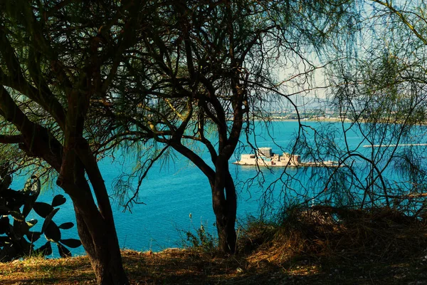 Ağaçların arasından Bourtzi kalesi, Nafplio, Yunanistan