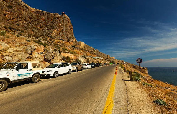 MONEMVASIA, GREECE - ECTOBER 05, 2015: Otomobil parkı ve Monemvasia 'nın ortaçağ kasabasının girişinin önündeki yol