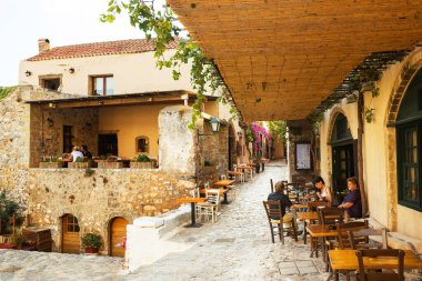 MONEMVASIA, GREECE - ECTOBER 05, 2015: Monemvasia arabasız bir ortaçağ kasabasındaki bir sokak kafesinde turistler