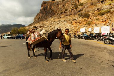 MONEMVASIA, GREECE - 08 Ekim 2015: Monemvasia, Moreloponnese, Yunanistan 'da arabasız bir ortaçağ turizm kasabasının girişinde inşaatçı ve yüklü atı