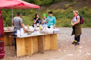 PLATEAU LAGO-NAKI, ADYGEYA, RUSSIA - SEPTEMBER 14, 2015: A group of tourists tasting honey on a mountain road in Adygea, Russia clipart