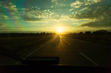 Yalnız araba gün batımının arka planında yol alır.