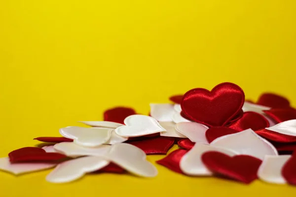 Pequeños corazones rojos y blancos que yacen en una pila sobre un fondo amarillo. —  Fotos de Stock