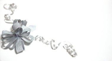 Köşedeki beyaz arka planda bulunan kurdeleli gümüş bir yay.