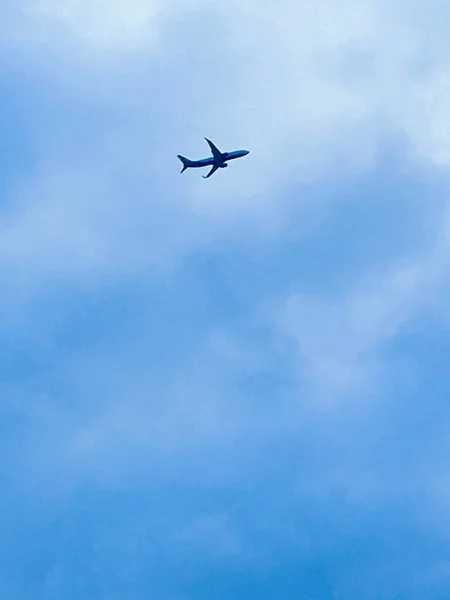 A plane that flies in the blue sky among the white lush clouds. Bright sunny day — Stock Photo, Image