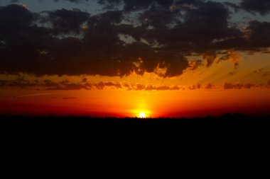 Koyu mavi bulutlara karşı gün batımı. Gün batımında kara tarla. 