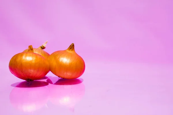 Tres bombillas se encuentran en la esquina izquierda sobre un fondo rosa. Vitaminas, espacio para texto en la esquina derecha. Tel de cebollas. —  Fotos de Stock