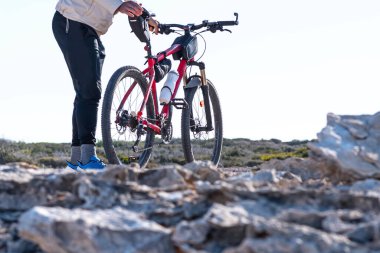 Kırmızı dağ bisikletini tarlada hazırlayan genç adama yaklaş..