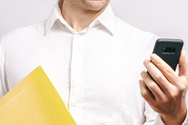 Closeup Man Holding Yellow Folder While Looking His Smartphone White — Stock Photo, Image