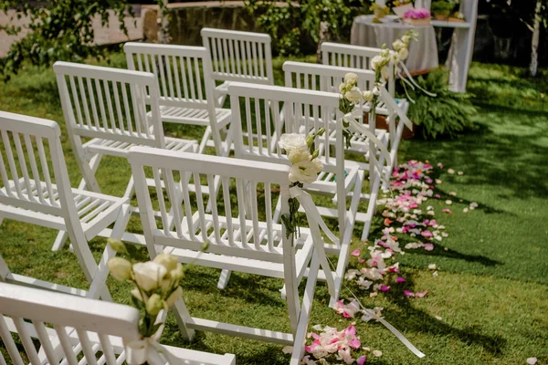 Hochzeitszeremonie im Freien, Stühle mit Blumen und Bändern stehen in Reihen auf dem Rasen — Stockfoto