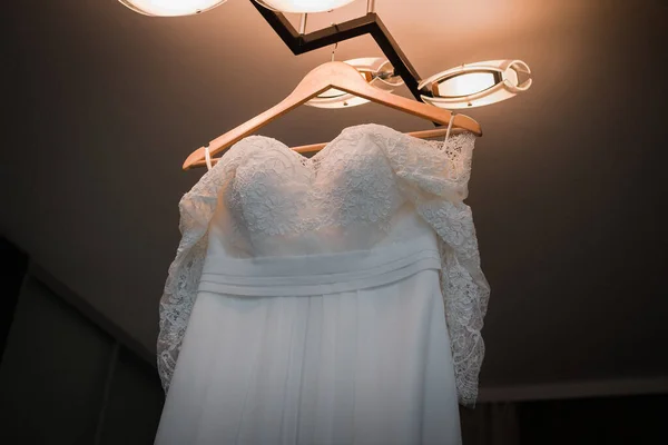 Bröllopsklänning hängande på ljuskronan i rummet — Stockfoto