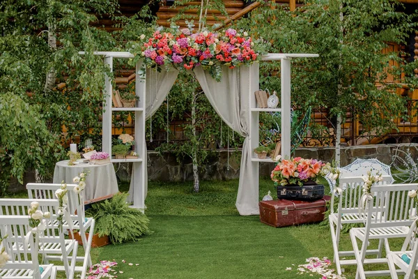 Bröllopsbåge av tyg och vita och rosa blommor på en grön naturlig bakgrund. Gamla dörrar, rustik stil Royaltyfria Stockbilder