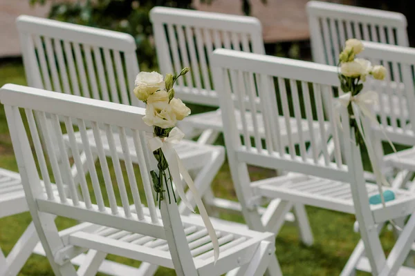 Outdoor wedding ceremony, chairs decorated with flowers and ribbons stand in rows on the grass — Stock Photo, Image
