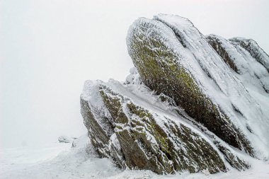 Romanya 'daki bir dağda karla kaplı antik bir taş