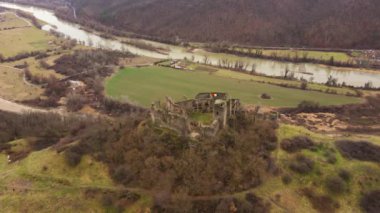 Arka planda nehir olan bir tepenin tepesindeki bir kalenin havadan çekilmiş görüntüleri. Bir ortaçağ kalesinin insansız hava aracı görüntüleri.