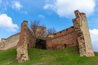 Ahşap kapıları ve tuğla duvarları olan eski bir ortaçağ kalesine eski, çökmüş bir giriş. Bir ortaçağ kale girişinin fotoğrafları.