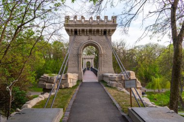 Romanya 'nın Craiova kentindeki parkta nehrin üzerinde asılı duran bir köprünün fotoğrafları. Parktaki askıya alınmış köprü.