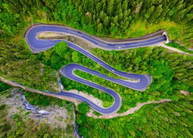 Dağlarda virajlı bir yol, yüksek irtifada ve alçak açılı bir drondan çekilmiş. Dağlardaki yılanlı bir yolun fotoğrafı..
