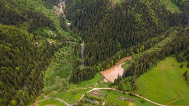 Neamt County, Romanya 'daki Kızıl Göl' de hava fotoğrafçılığı. Göl manzaralı bir drondan alınan manzara fotoğrafçılığı, kamera açısı yere doğru alçalır. Kuşların gözü dağ gölü ve çam ormanlarının üzerinde.