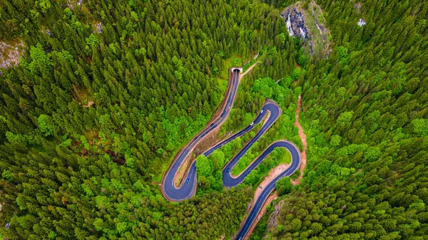 Dağlarda virajlı bir yol, yüksek irtifada ve alçak açılı bir drondan çekilmiş. Dağlardaki yılanlı bir yolun fotoğrafı..