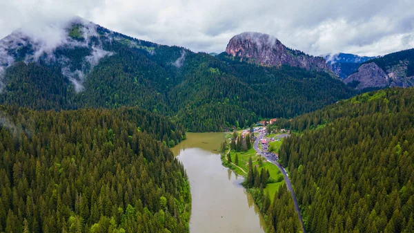 Aerial photography of Red lake in Romania, Neamt county. Panorama photography taken from a drone with view of the lake, clouds and mountains in the background. Birds eye view over mountain lake