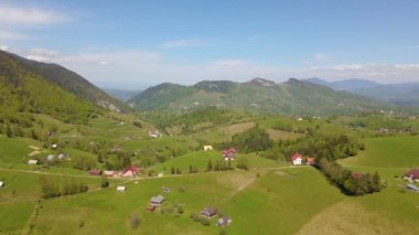 Romanya 'nın Brasov kentindeki Pestera kasabasına kuşların bakış açısı. Arka planda dağlar olan köyün üzerindeki insansız hava aracı görüntüleri. Güzel bir dağ köyünün hava videosu..