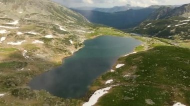 İHA 'dan çekilen bir dağ gölünün havadan çekilmiş videosu. Arka planda güzel dağlar var. Görüntüler, Romanya 'nın Hunedoara kentindeki Bucura Gölü üzerindeki bir İHA' dan çekildi..