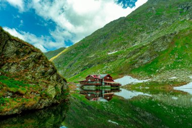 Buzul gölü kıyısındaki dağlarda bir kulübenin fotoğrafı. Fotoğraf yazın güzel havalarda çekilmiştir. Hala dağlarda bir dağ evinde Gölün yanında.