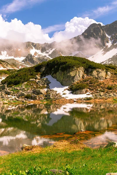 Lovely portrait photography of a mountain lake with mountain peaks in the background. Weather is sunny with a couple pf clouds. Glacial lake in the mountains landscape in summer