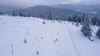 Aerial view of a small resort on top of the mountain in winter season at sunset. Photography was shot from a drone at a higher altitude. Aerial view of a resort in winter at sunset